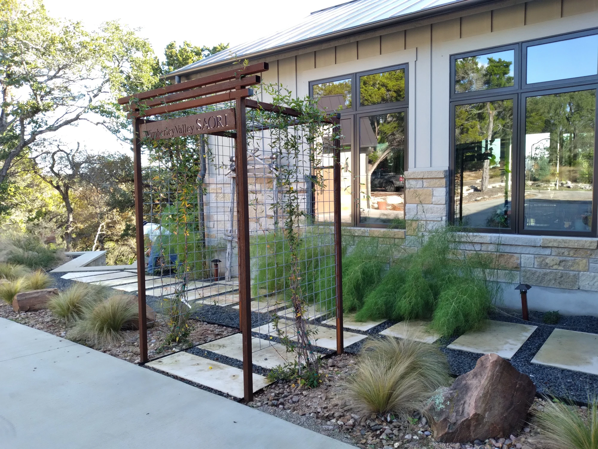 Steel arbor framing a garden path beside a home